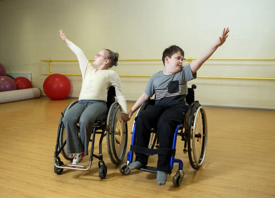 Two disabled friends in wheelchairs in a dance class