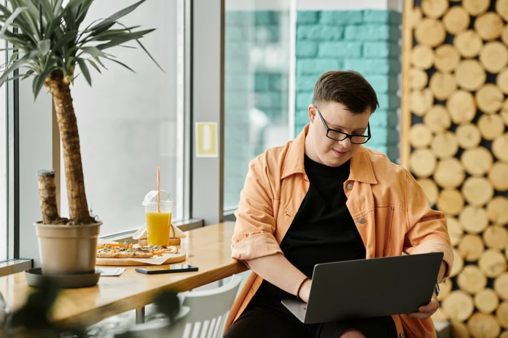 Disabled man with down syndrome using laptop while at café