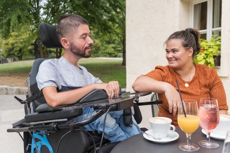 Disabled man in wheelchair at café with support worker